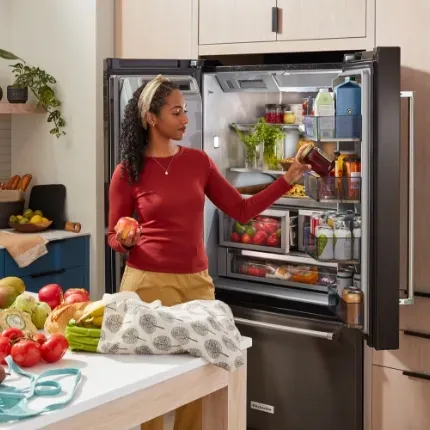 woman wearing a red top and headband, taking out sauce condiment from refrigerator
